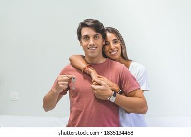 Young smiling couple holding their new house keys, real estate and relocation concept.