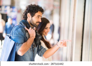 Young Smiling Couple Shopping In An Urban Street. Shallow Depth Of Field, Focus On The Man