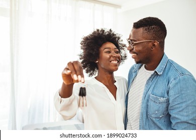 Young smiling couple showing keys to new home hugging looking at camera. Happy couple showing keys of new home. Happy young couple at their new house front door proud to show home keys