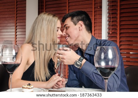 young smiling couple is sitting at restaurant. key are in the hand of man