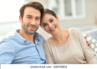Junge lächelnde Paare sitzen zu Hause auf dem Sofa