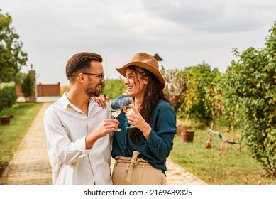Young smiling couple tasting wine at winery vineyard - Friendship and love concept with young people enjoying harvest time 