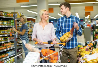 Young smiling customers choosing fresh frusits in food store
