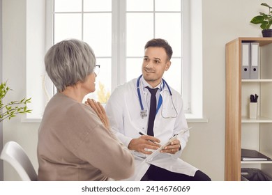 Young smiling doctor, male nurse taking care of old woman listening during check, examination. Man monitoring resident of nursing home, patient in hospital, clinic, maintain elderly health and safety - Powered by Shutterstock