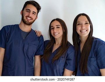 Young Smiling Doctors Dentists In Dark Blue Uniform Standing In Hallway