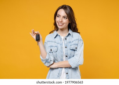 Young smiling dreamful pensive wistful happy rich brunette woman 20s wearing stylish denim shirt white t-shirt holding in hands car keys look aside isolated on yellow color background studio portrait - Shutterstock ID 1977906563