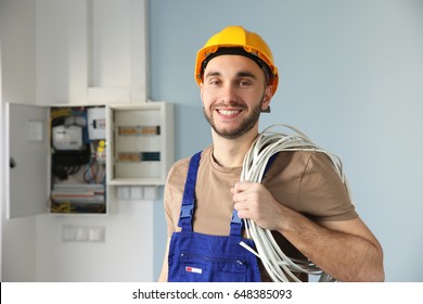 Young Smiling Electrician With Bunch Of Wires Indoors