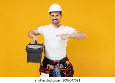 Young Smiling Employee Handyman Man In Protective Helmet Hardhat Point Index Finger On Tool Case Box Isolated On Yellow Background Instruments Accessories Renovation Apartment Room Repair Home Concept