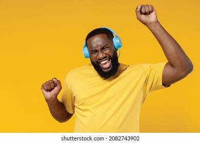 Young Smiling Excited Happy Black Man 20s Wearing Bright Casual T-shirt Headphones Listen To Music Dancing Have Fun Isolated On Plain Yellow Color Background Studio Portrait. People Lifestyle Concept