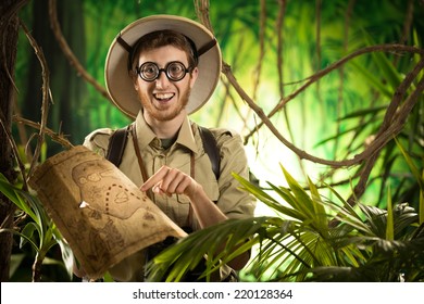 Young Smiling Explorer In The Jungle With Thick Glasses Holding A Map.