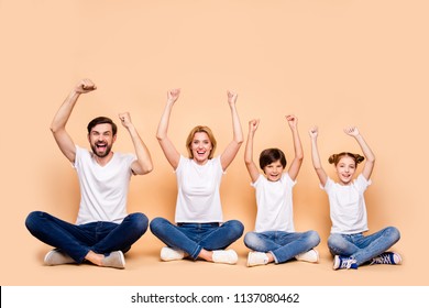 Young smiling family, bearded father, blonde mother, little boy and girl wearing blue jeans and white T-shirts, sitting in odrer of hierarchy in lotus pose raising up hands - Shutterstock ID 1137080462