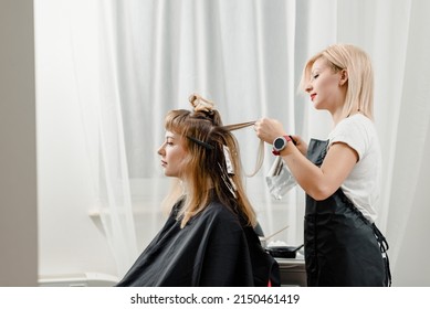 Young smiling female hairdresser painting woman's hair in new color - Powered by Shutterstock