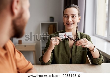 Young smiling female tutor pointing at paper card with Chinese hieroglyph meaning zero