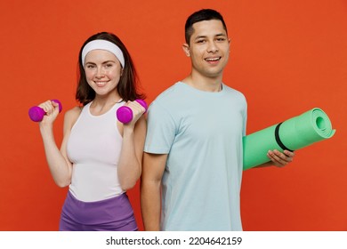 Young smiling fitness trainer instructor sporty two man woman in headband t-shirt hold dumbbell yoga mat spend weekend in home gym isolated on plain orange background Workout sport lifestyle concept - Powered by Shutterstock