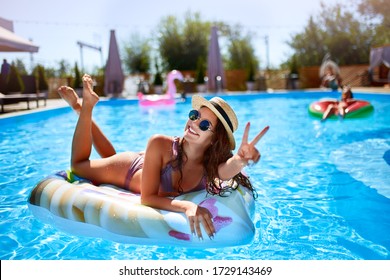 Young Smiling Fitted Girl In Bikini, Straw Hat Relax On Inflatable Swan In Swimming Pool. Attractive Woman In Swimwear Lies In The Sun On Tropical Vacation. Pretty Female Sunbathing At Luxury Resort.