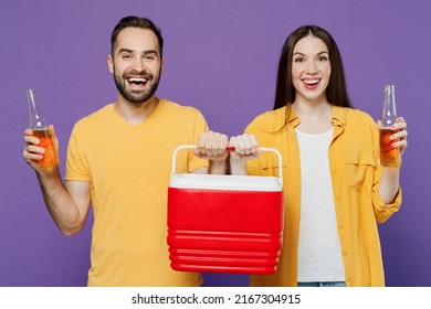 Young Smiling Fun Cool Couple Two Friends Family Man Woman Together Wear Yellow Clothes Hold Red Box Freezer Cooler Refrigerator Bottle Drink Beer Isolated On Plain Violet Background Studio Portrait