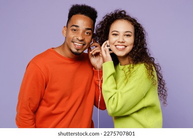 Young smiling fun couple two friends family man woman of African American ethnicity wear casual clothes together listen to music share same headphones isolated on pastel plain light purple background - Powered by Shutterstock