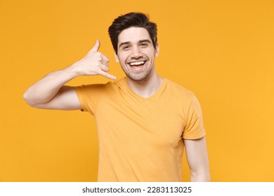 Young smiling fun friendly unshaved caucasian handsome man 20s wears casual basic blank print design t-shirt doing phone finger gesture like call me back isolated on yellow background studio portrait - Shutterstock ID 2283113025
