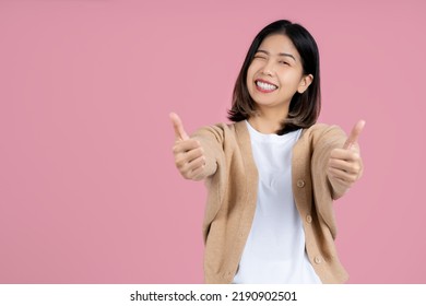 Young Smiling Fun Happy Woman Of Asian Showing Thumb Up Like Gesture Blink Isolated On Pink Background Studio Portrait. People Lifestyle Concept