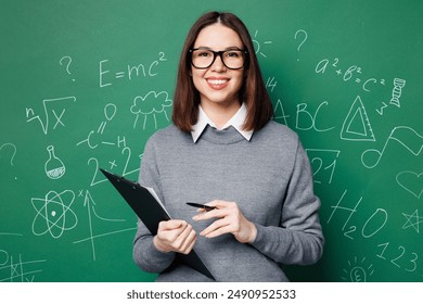 Young smiling fun smart teacher woman wear grey casual shirt glasses clipboard with paper documents isolated on green wall chalk blackboard background studio. Education in high school college concept - Powered by Shutterstock