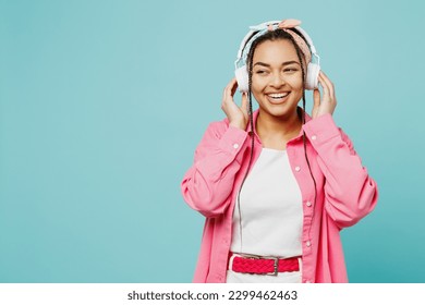 Young smiling fun woman of African American ethnicity wear pink shirt white t-shirt headscarf headphones listen to music look aside isolated on plain pastel light blue cyan background studio portrait - Powered by Shutterstock