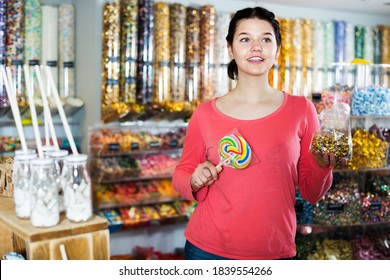 Young smiling girl choosing candies for gift in sweets shop