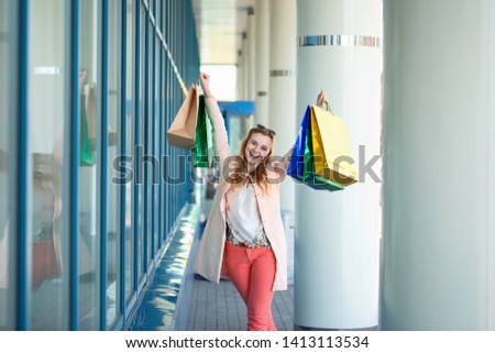 A young smiling girl enjoys a successful shopping, walking down the street with bags in her hands