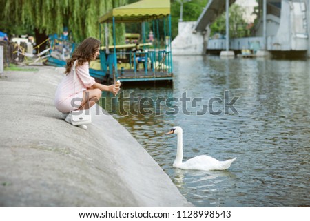 young smiling girl with ice cream near lake with swan