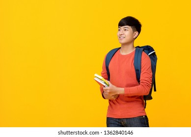 Young Smiling Handsome Asian Male College Student With Backpack Holding Books Studio Shot For Education Concept