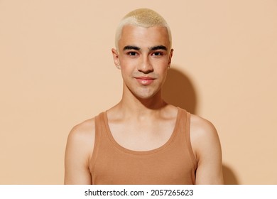 Young Smiling Happy Blond Latin American Hispanic Gay Man 20s With Make Up In Beige Tank Shirt Looking Camera Isolated On Plain Light Ocher Background Studio Portrait People Lgbt Lifestyle Concept.