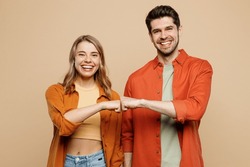 Young Smiling Happy Buddies Fun Couple Two Friends Family Man Woman Wear Casual Clothes Looking Camera Giving Fist Bumo Together Isolated On Pastel Plain Light Beige Color Background Studio Portrait