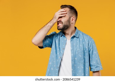 Young smiling happy caucasian man 20s in blue shirt white t-shirt put hand on face facepalm epic fail mistaken omg gesture isolated on plain yellow background studio portrait. People lifestyle concept
