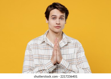 Young Smiling Happy Caucasian Man 20s Wearing White Casual Shirt Hands Folded In Prayer Gesture, Begging About Something Isolated On Plain Yellow Background Studio Portrait. People Lifestyle Concept