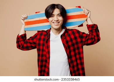 Young smiling happy cheerful man of Asian ethnicity he wear red shirt casual clothes hold skateboard pennyboard look camera isolated on plain pastel light beige background studio. Lifestyle concept - Powered by Shutterstock