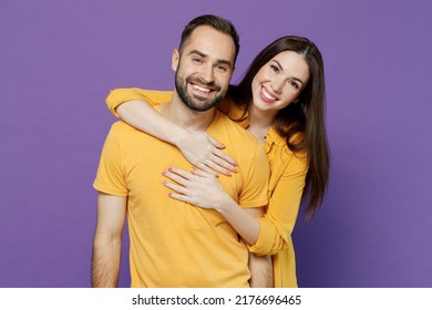 Young Smiling Happy Cheerful Nice Lovely Couple Two Friends Family Man Woman 20s Together Wearing Yellow Casual Clothes Looking Camera Hud Cuddle Isolated On Plain Violet Background Studio Portrait.