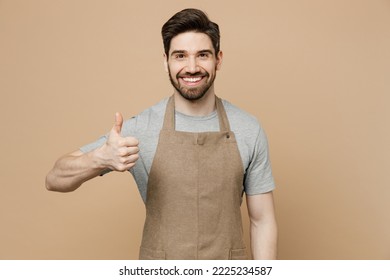 Young smiling happy cool man barista barman employee wear brown apron work in coffee shop showing thumb up like gesture isolated on plain pastel light beige background. Small business startup concept - Powered by Shutterstock