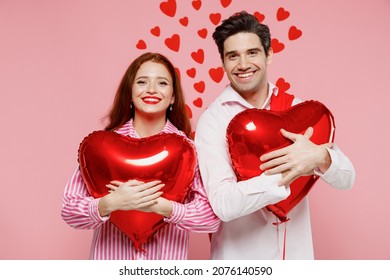 Young Smiling Happy Couple Two Friends Woman Man In Shirt Hold Hug Red Bunch Of Inflatable Balloons Isolated On Plain Pink Background Studio Portrait. Valentine's Day Birthday Holiday Party Concept.