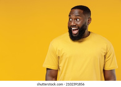 Young Smiling Happy Fun Black Man 20s Wearing Bright Casual T-shirt Look Aside On Copy Space Workspace Area Mock Up Isolated On Plain Yellow Color Background Studio Portrait. People Lifestyle Concept