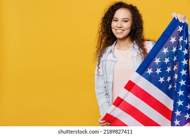 Young Smiling Happy Fun Black Teen Girl Student She Wears Casual Clothes Backpack Bag Hold American Us Flag Look Camera Isolated On Plain Yellow Color Background High School University College Concept