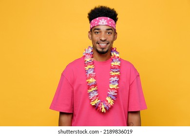 Young Smiling Happy Fun Cool Cheerful Satisfied Man 20s He Wearing Pink T-shirt Hawaiian Lei Bandana Near Hotel Pool Look Camera Isolated On Plain Yellow Background. Summer Vacation Sea Rest Concept