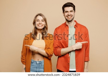 Young smiling happy fun couple two friends family man woman wear casual clothes point index finger aside ona rea mock up together isolated on pastel plain light beige color background studio portrait Zdjęcia stock © 