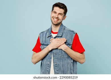 Young smiling happy fun grateful man he wearing denim vest red t-shirt casual clothes put folded hands on heart isolated on plain pastel light blue cyan background studio portrait. Lifestyle concept - Powered by Shutterstock