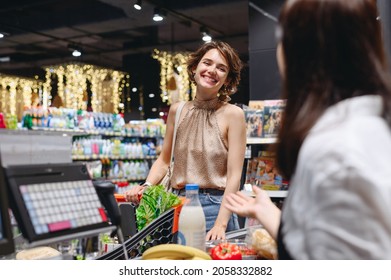 Young Smiling Happy Fun Woman In Casual Clothes Shopping At Supermaket Store With Grocery Cart Stand At Store Checkout Pay Give Money To Cashier Inside Hypermarket Purchasing Gastronomy Food Concept