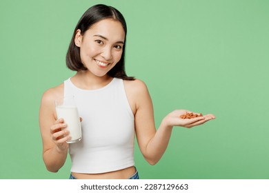 Young smiling happy fun woman wearing white clothes hold in hand almond nuts milk in glass isolated on plain pastel light green background. Proper nutrition healthy fast food unhealthy choice concept - Powered by Shutterstock