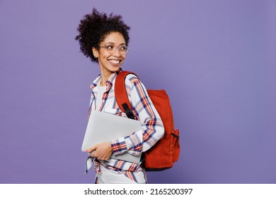 Young Smiling Happy Girl Woman Of African American Ethnicity Teen Student In Shirt Backpack Hold Use Work On Laptop Pc Computer Look Aside On Workspace Area Mock Up Isolated On Plain Purple Background