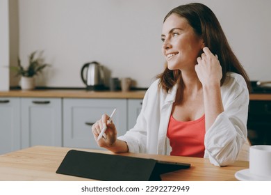 Young smiling happy housewife woman wear casual clothes graphic designer hold in hand work use write draw stylus pc pen eat breakfast cooking food in light kitchen at home alone. Healthy diet concept - Powered by Shutterstock