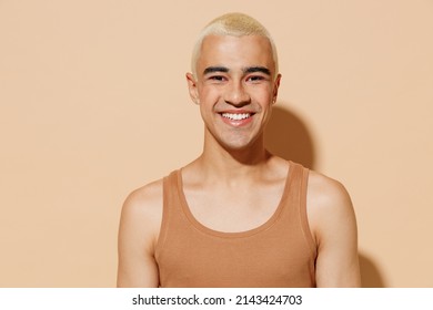 Young Smiling Happy Laughing Blond Latin American Gay Man 20s With Make Up In Beige Tank Shirt Looking Camera Isolated On Plain Light Ocher Background Studio Portrait People Lgbt Lifestyle Concept.