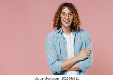 Young Smiling Happy Man 20s With Long Curly Hair Wear Blue Shirt White T-shirt Glasses Hold Hands Crossed Folded Isolated On Pastel Plain Pink Color Wall Background Studio. People Lifestyle Concept.