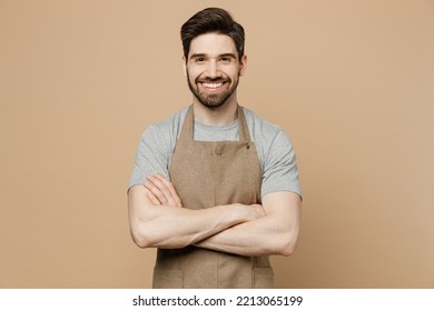 Young smiling happy man barista barman employee wear brown apron work in coffee shop hold hand crossed folded look camera isolated on plain pastel light beige background Small business startup concept - Powered by Shutterstock