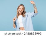 Young smiling happy positive cool woman she wears white top shirt casual clothes raise up hands dance have fun isolated on plain pastel light blue cyan background studio portrait. Lifestyle concept